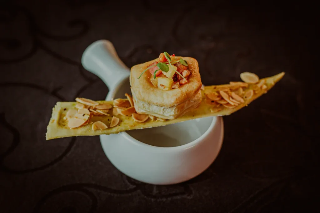 aperitivo gourmet com massa folhada recheada e crocante com amêndoas fatiadas em prato branco