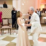 Bodas de prata: como comemorar 25 anos de casamento Casal idoso dançando em festa elegante com convidados ao fundo e pétalas caindo