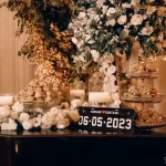 10 lembrancinhas de casamento que seus convidados vão amar! decoração de casamento com flores brancas, doces dourados, velas e placa com data 06-05-2023