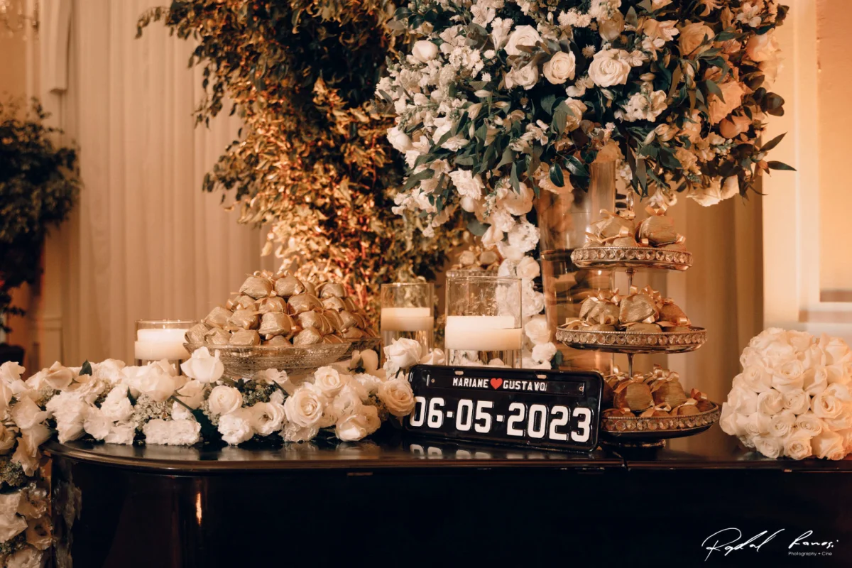 decoração de casamento com flores brancas, doces dourados, velas e placa com data 06-05-2023