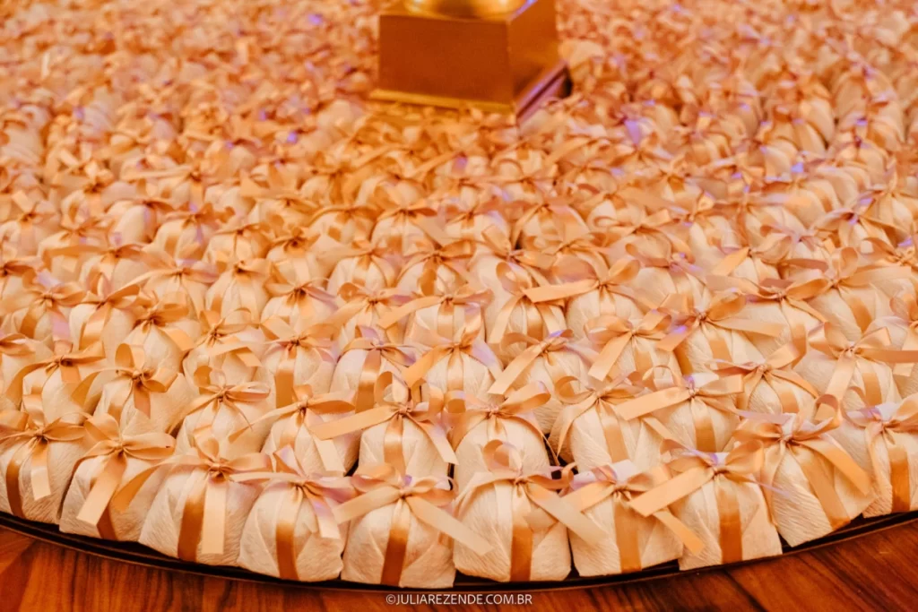 Lembrancinhas de casamento com embalagem branca e laço dourado organizadas em círculo