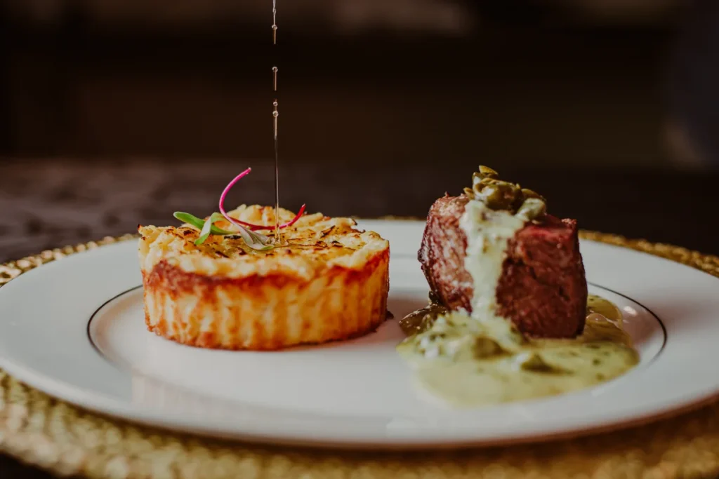 Prato gourmet com purê gratinado e pedaço de carne com molho cremoso
