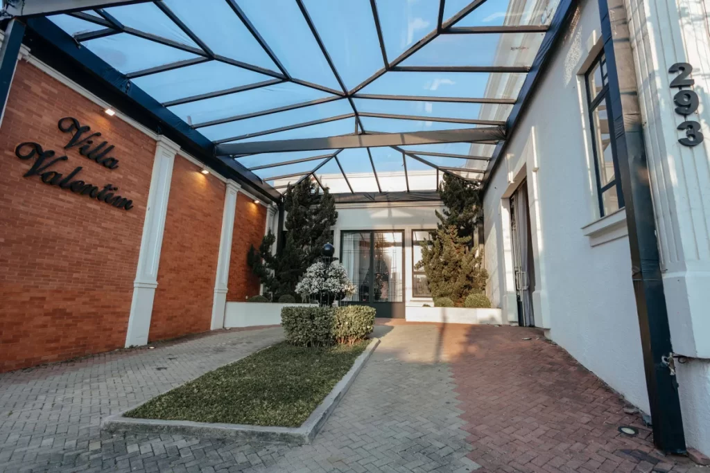 Entrada da Villa Valentim com teto de vidro e jardim central
