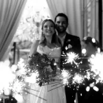 Guia completo da festa de casamento perfeita e inesquecível! Casal de noivos comemorando casamento com fogos de artifício em festa de casamento elegante.
