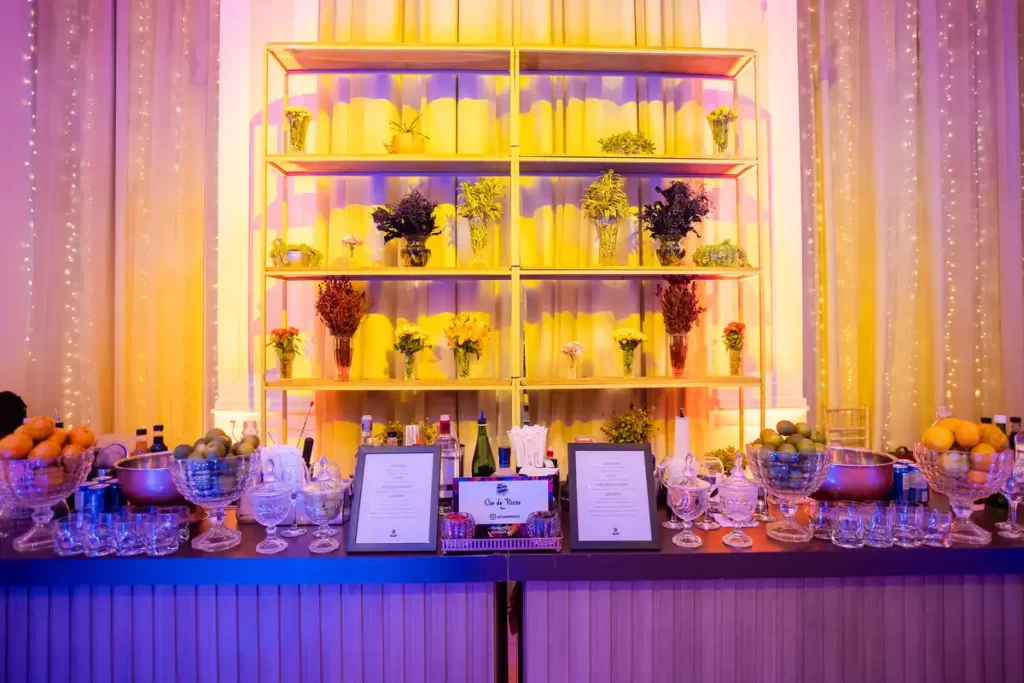 decoracao de evento corporativo com plantas flores amarillas Mesa decorada com plantas e flores amarelas sob iluminação colorida.