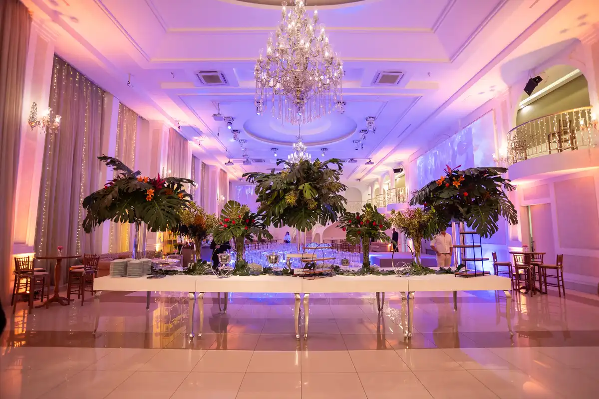 Decoração elegante para eventos corporativos em salão sofisticado com iluminação colorida, cristaleira e arranjos florais decorativos.