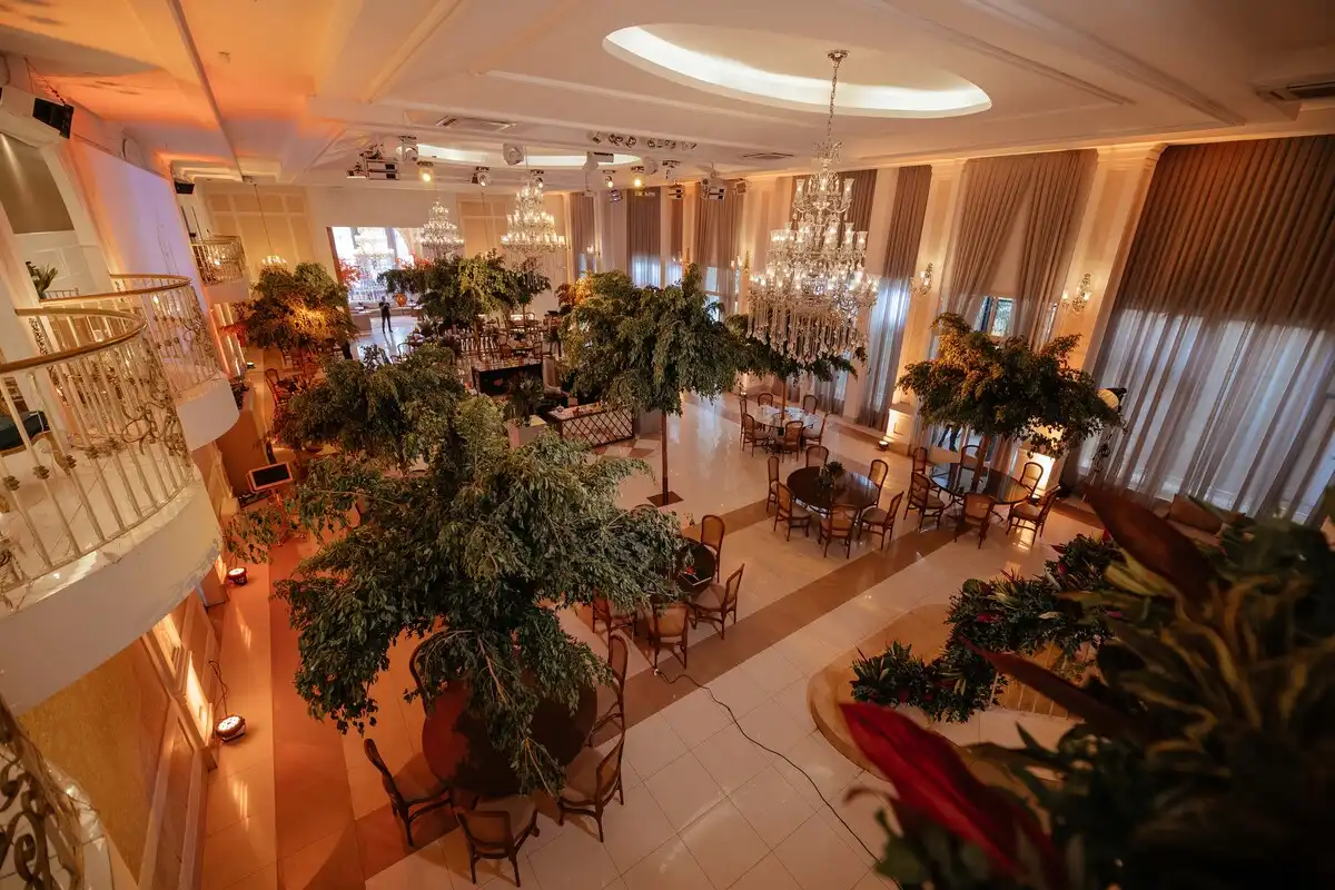 Salão de festas elegante decorado com árvores artificiais e iluminação sofisticada ideal para eventos especiais