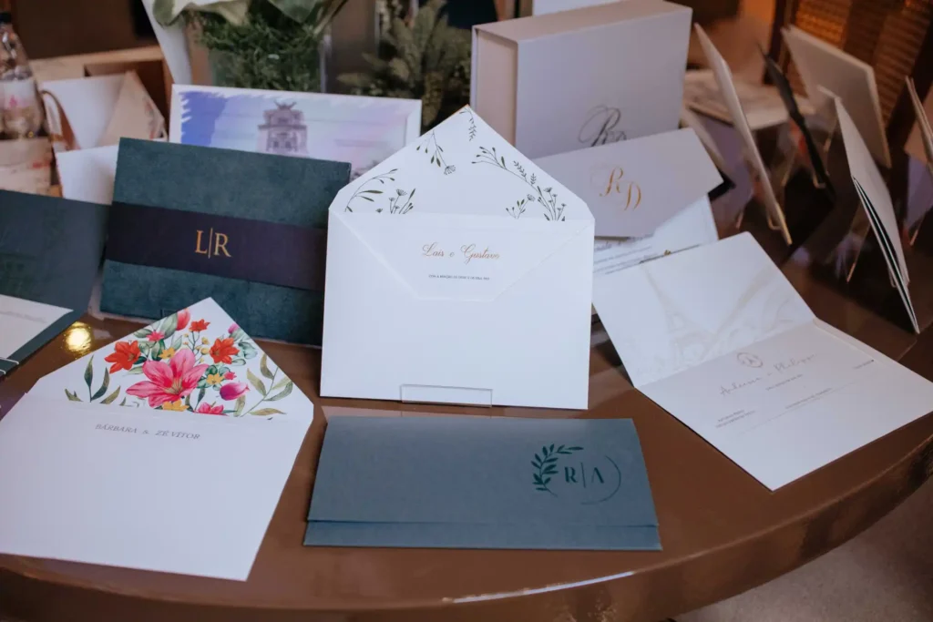 Convite de casamento com design elegante, envelopes decorados e detalhes em dourado e floral.