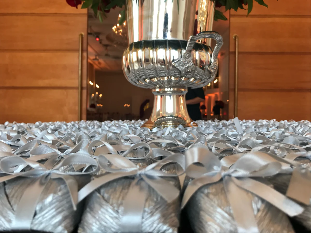 Bem casados com laços prateados em frente a vaso decorativo prateado