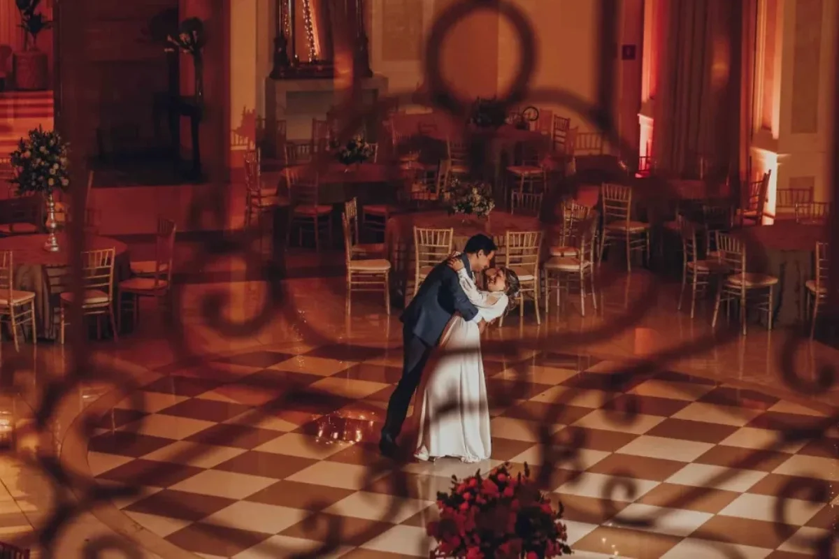 Casal dançando em salão de casamento com piso quadriculado e decoração elegante