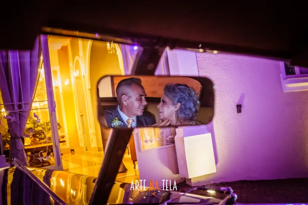 Casal maduro apaixonado refletido no espelho retrovisor de carro clássico em ambiente iluminado à noite