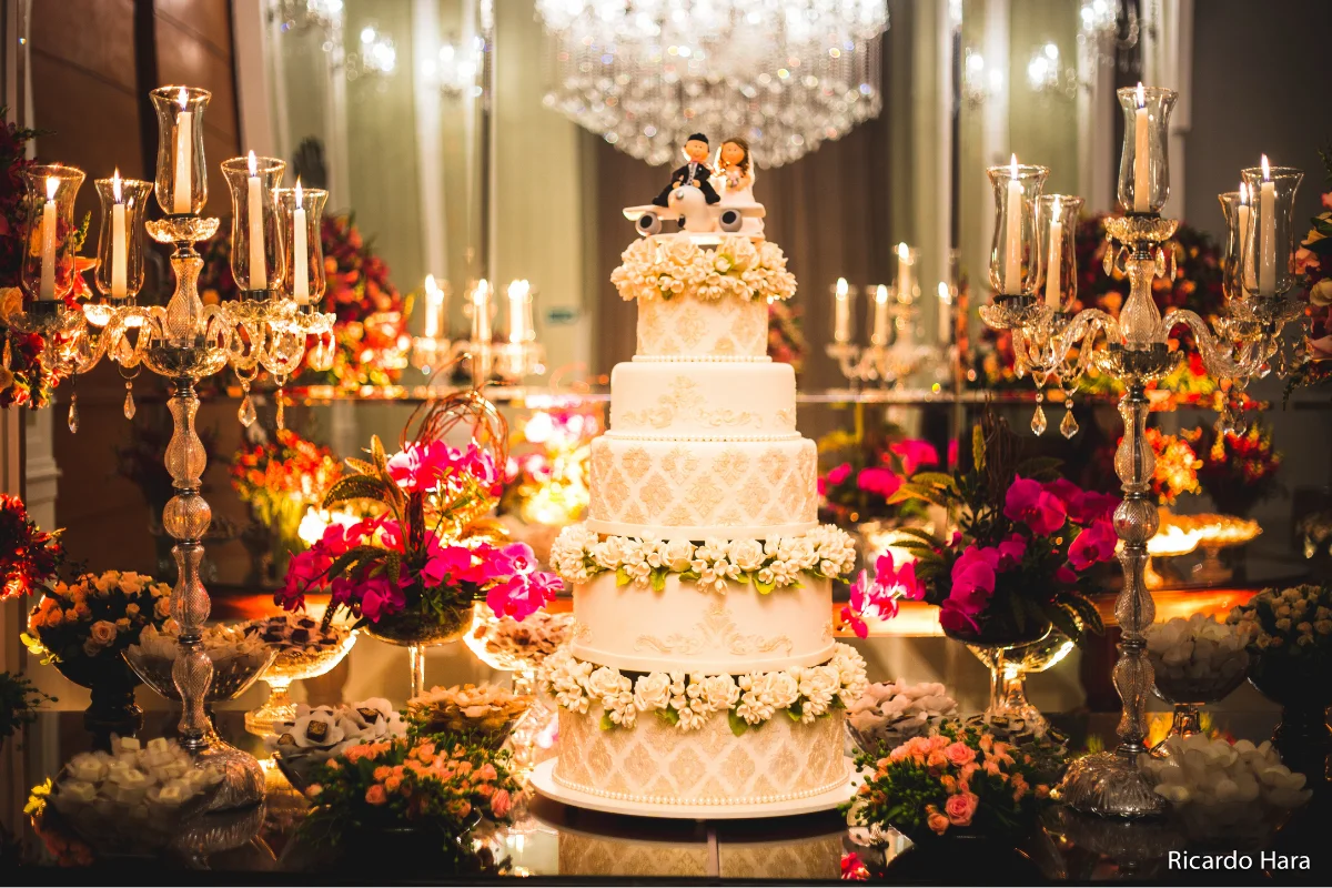 Bolo de casamento com cinco andares e flores no topo com boneco dos noivos
